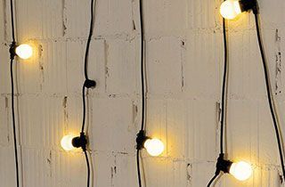 Guirnalda de luces cálidas colgada en pared blanca